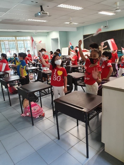 Pupils waving the Singapore flag with pride and excitement during the songs session.